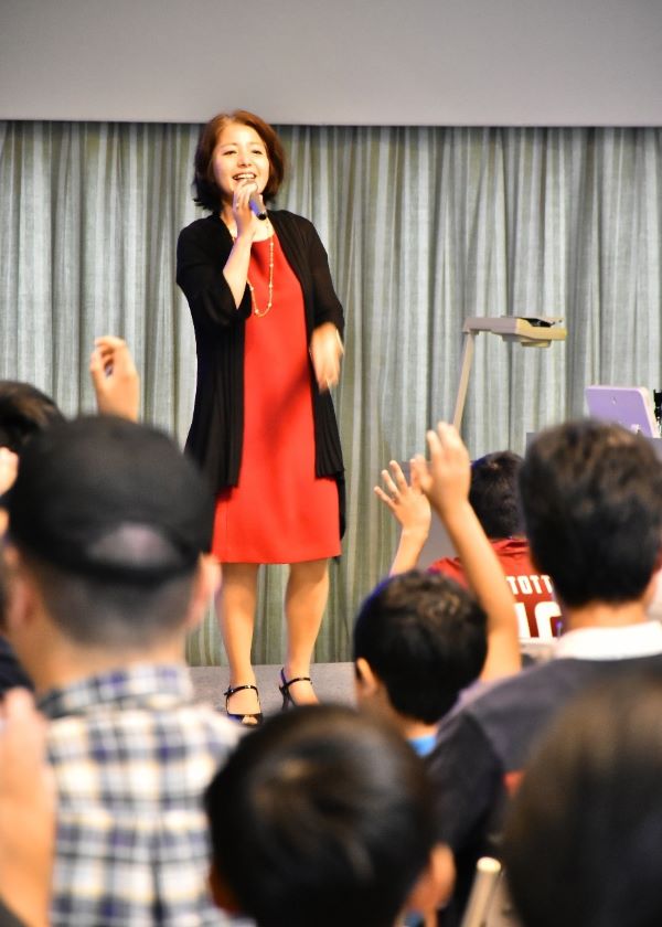 Miwa holding a microphone on stage at a STEM conference. 